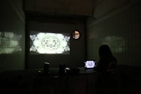 a woman is standing in front of a projection screen in a dark room