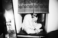 a black and white photo of a man sitting in front of a mirror