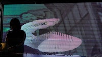 a woman standing in front of a large projection screen