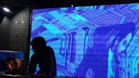a person standing in front of a large projection screen